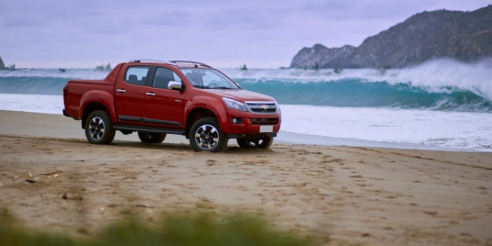 camioneta chevrolet color rojo en la arena junto al mar